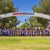 Several college students throw their caps into the air under an archway with the words Arizona Wildcats on it.